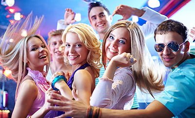 Portrait of glamorous girls dancing at party with happy friends near by